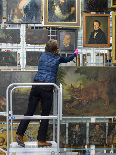 Eine Mitarbeiterin bringt ein Gemälde zurück ins Depot.