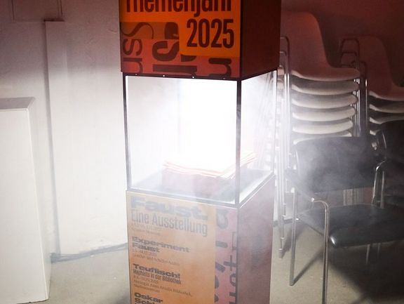 Stele mit Magazinen, aus der weißes Licht und Rauch strömen.