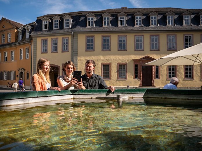 Drei Personen stehen vor dem Brunnen vor dem Goethe Nationalmuseum.