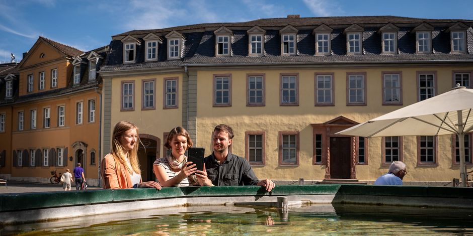 Drei Personen stehen vor dem Brunnen vor dem Goethe Nationalmuseum.