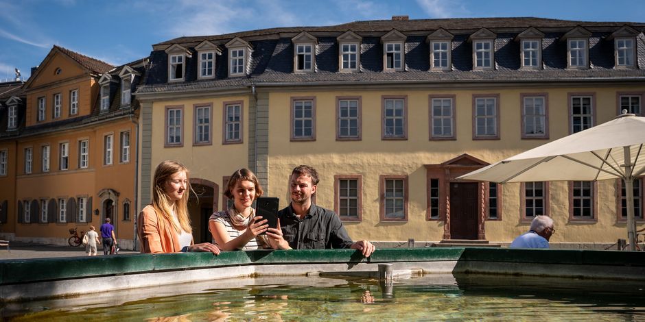 Drei Personen stehen vor dem Brunnen vor dem Goethe Nationalmuseum.
