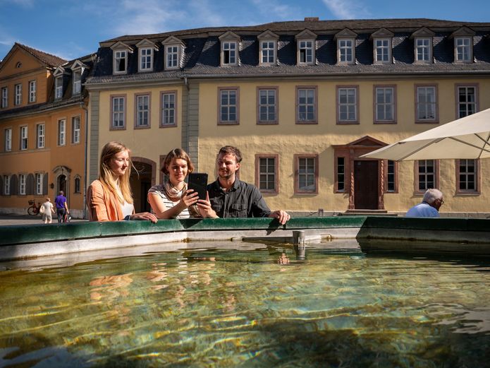 Drei Personen stehen vor dem Brunnen vor dem Goethe Nationalmuseum.