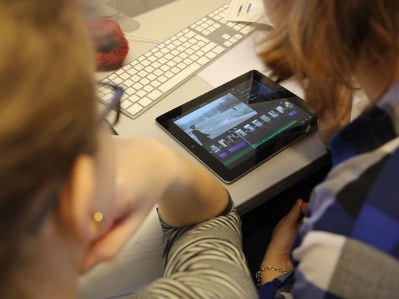 Young people editing a short film on a tablet for a project