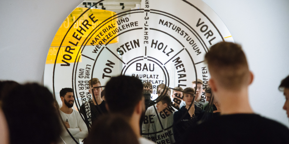A group of young people standing in front of a round mirror installation