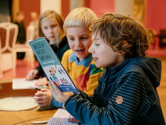 Drei Kinder lesen ein Heft
