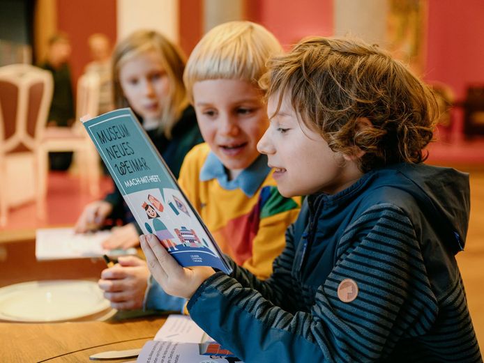 Drei Kinder lesen ein Heft