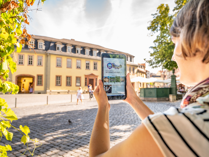 Frau mit Tablet auf dem die App Weimar+ geöffnet ist