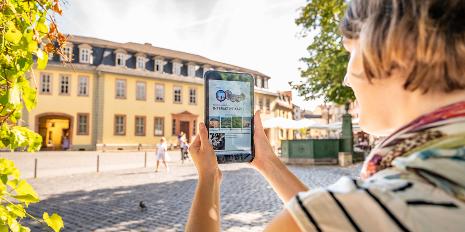 Frau mit Tablet auf dem die App Weimar+ geöffnet ist