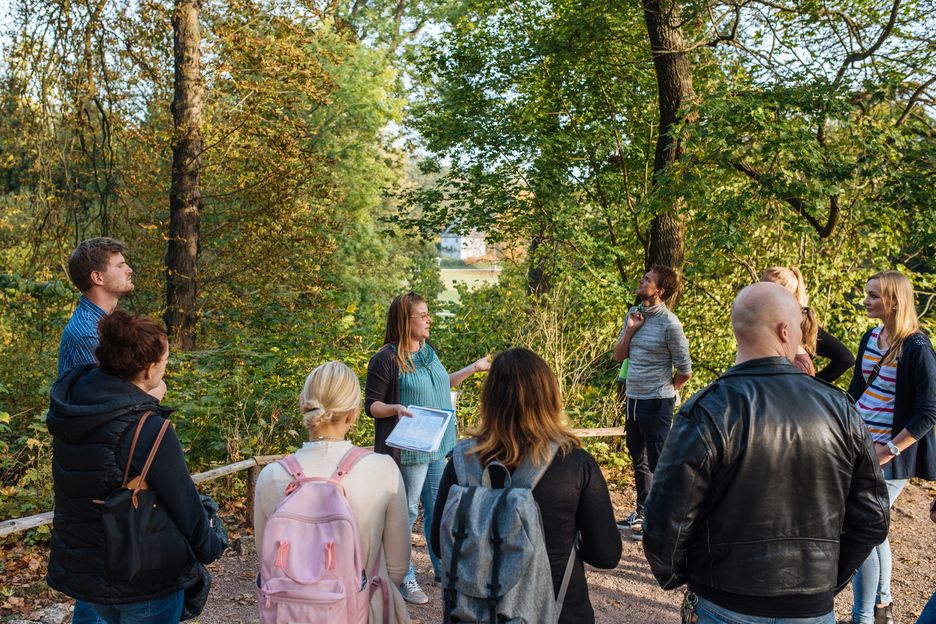 Bildung und Vermittlung Gruppe Erwachsener steht um einen Guide in einer Parkkulisse