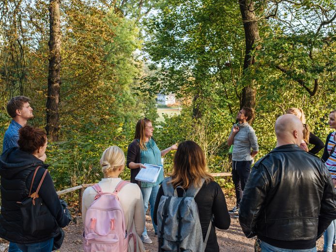 Gruppe Erwachsener steht um einen Guide in einer Parkkulisse