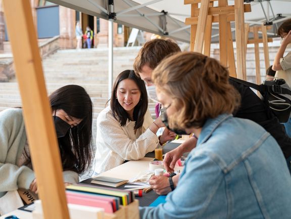 Kinder probieren sich an Bastelarbeite an einem mobilen Stand