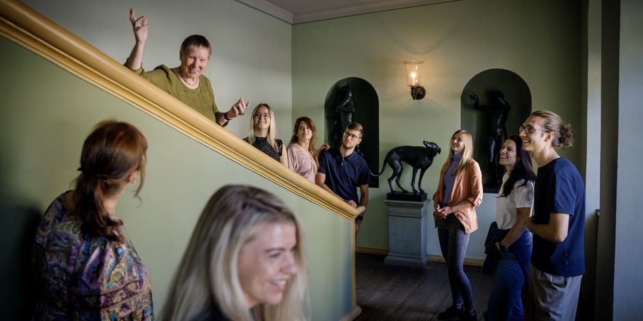A group with guide stops on a staircase to look at sculptures and paintings