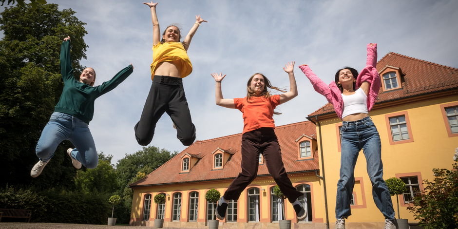 Junge Menschen springen vor dem Wielandgut Oßmannstedt in die Höhe