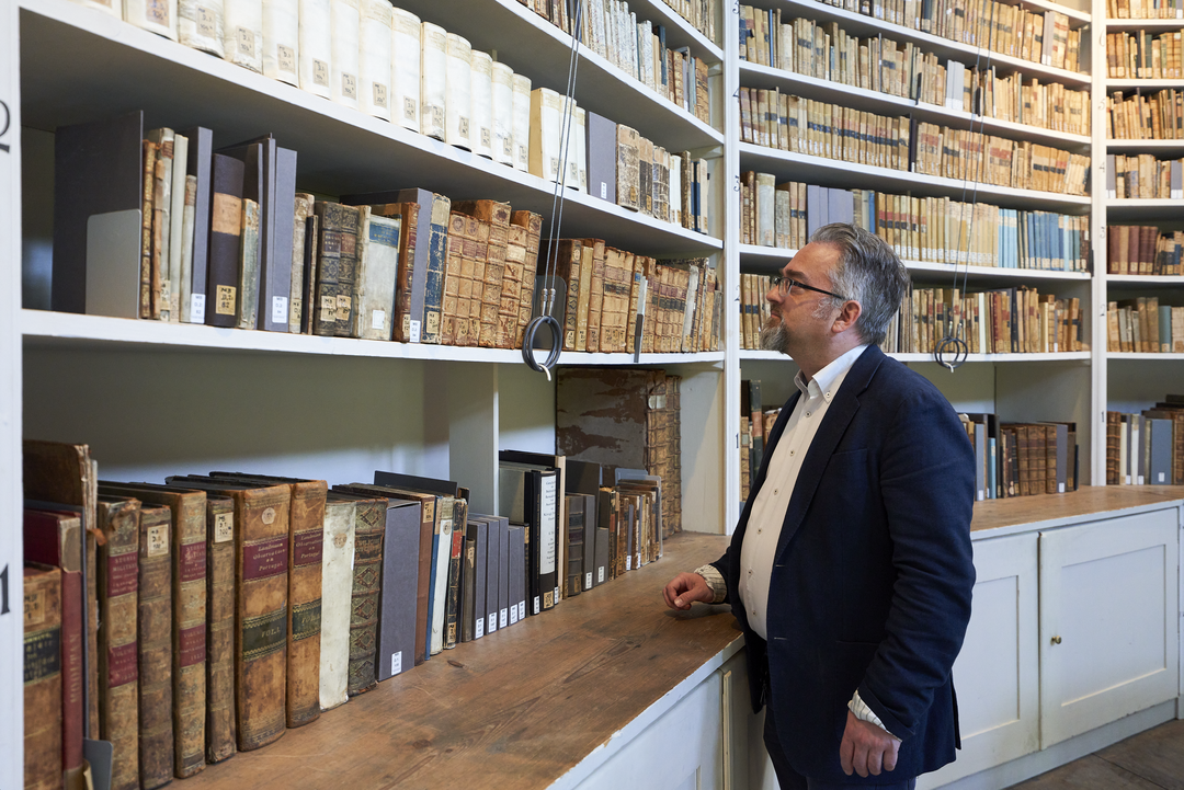 Prof. Dr. Marian Füssel vor einem Bücherregal im Rokokosaal der Herzogin Anna Amalia Bibliothek