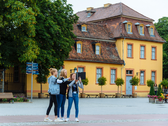 Drei Mädchen stehen auf dem Theaterplatz vor dem Wittumspalais und nehmen mit dem Tablet Fotos auf.