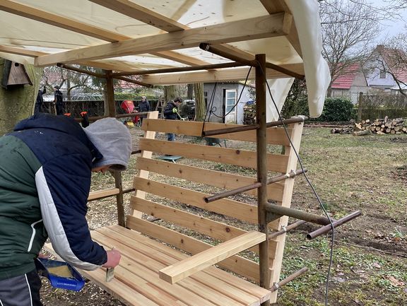 Ein Junge lackiert eine Holzbank