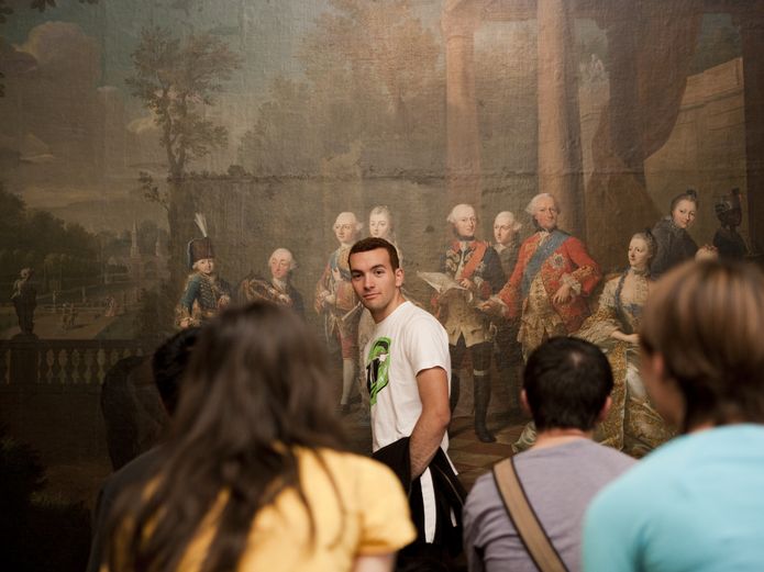 junger Mann steht bei einer Gruppenführung vor einem Gemälde