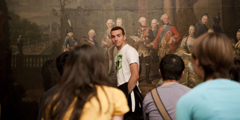 junger Mann steht bei einer Gruppenführung vor einem Gemälde