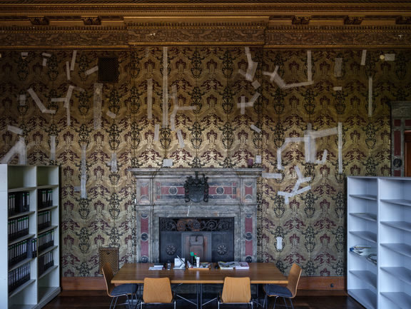 A meeting room with an old fireplace and ornate wallpaper