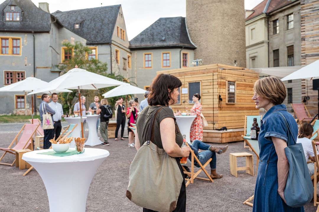 Menschen stehen an Stehtischen vor dem Weimarer Schloss. Sie unterhalten sich.