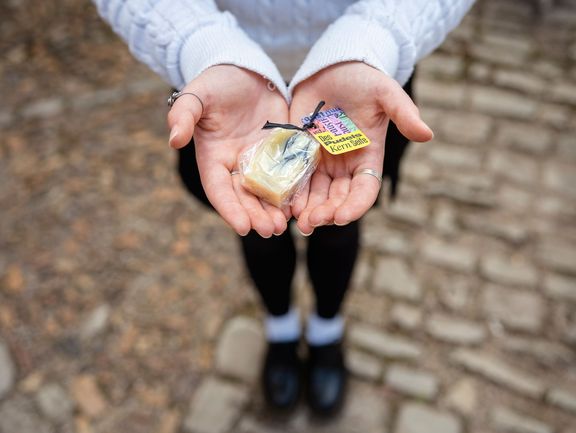 in zwei Händen liegt ein verpacktes Stück Seife.