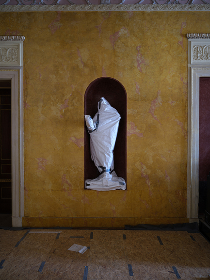 A white sculpture in a niche framed in a yellow wall
