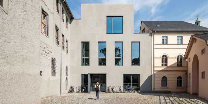 Blick auf den Eingang des Studienzentrums mit Fahrrädern und Besucherin