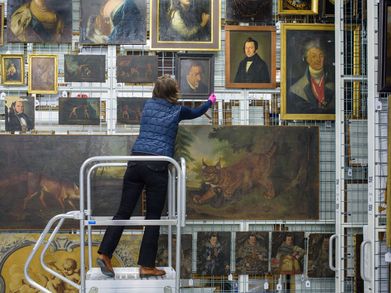 Eine Mitarbeiterin bringt ein Gemälde zurück ins Depot.