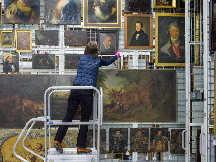 Curator hanging a painting in the storage facility