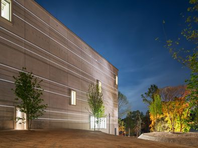 Außenansicht des Bauhaus-Museums Weimar am Abend mit leuchtenden Lichtbändern an der Fassade