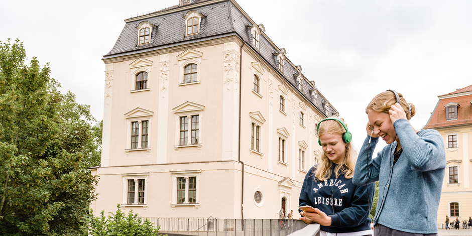 Zwei Frauen lachen und unterhalten sich gut beim Anhören eines Audiowalks