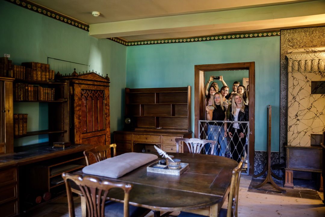 Foto vom einem Arbeitszimmer mit Schreibutensilien auf die Besuchermenge, die sich am Türrahmen eingefunden hat