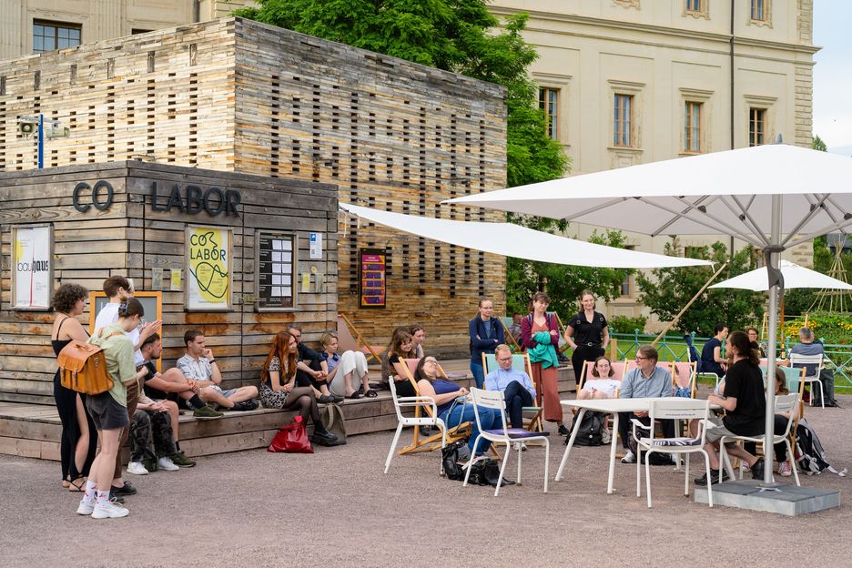 Eine Gruppe junger Menschen sitzt vor dem Co-Labor, um gemeinsam aus Büchern vorzulesen
