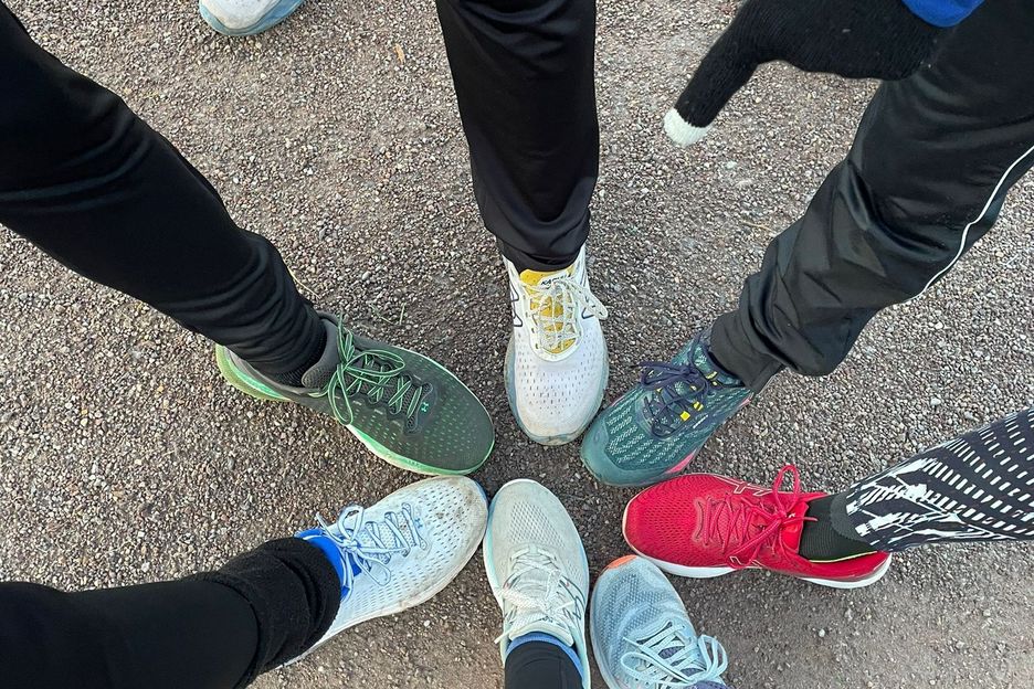 Mehrere Füße von oben betrachtet und mit Laufschuhen bekleidet berühren sich an den Fußspitzen und bilden einen Kreis