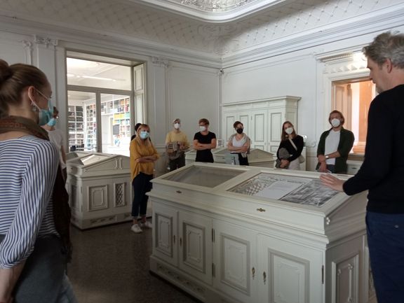 Teilnehmerinnen und Teilnehmer des Sommerkurses 2021 bei einer Führung durch das Goethe- und Schiller-Archiv mit Alexander Rosenbaum; Betrachtung der Vitrinen im Mittelsaal