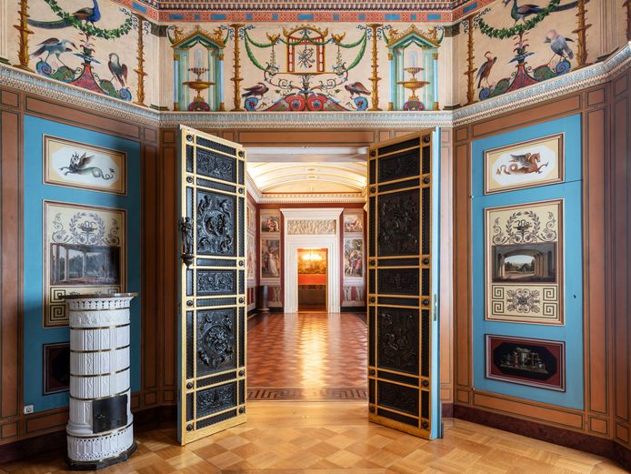 Magnificently designed round room with blue walls allows a view through a black double door onto a gallery