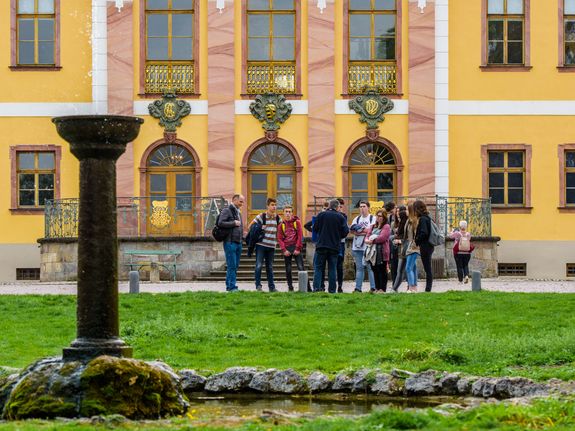 Eine Schülergruppe steht im Kreis aufgestellt vor dem Schloss Belvedere