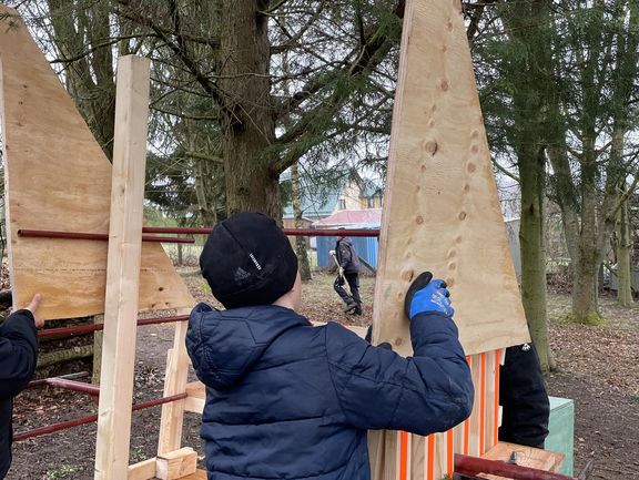 Ein Kind baut an der Überdachung einer Holzbank