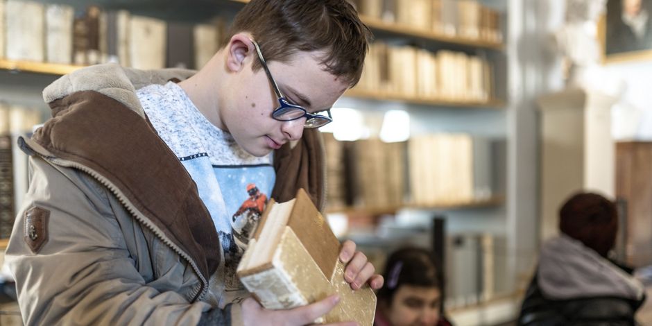 Un garçon handicapé examine un livre de la bibliothèque historique