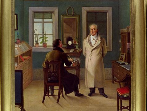 Zwei Personen in einem Arbeitszimmer neben einem Fenster.