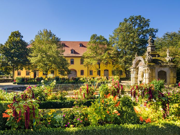 Blick über Blumenbeete und Brunnenhof auf das Gutshaus