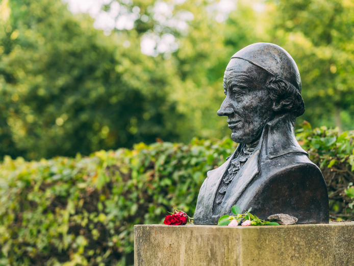 Eine dunkel gehaltene Büste von Wieland, vor die eine rote Blume glegt wurde