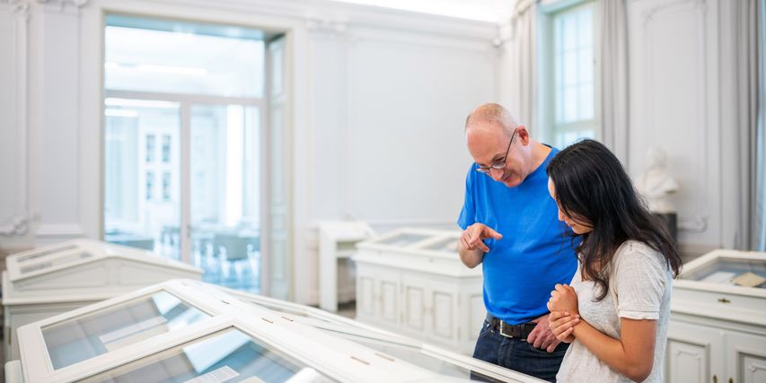 Besucher betrachten die Vitrinen im Mittelsaal
