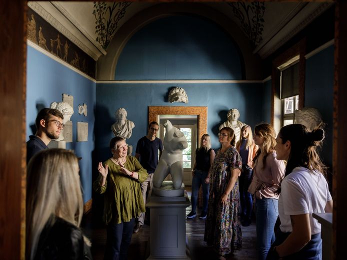Ein gestikulierender weiblicher Guide steht im Zentrum einer Besuchergruppe inmitten eines Raumes mit Skulpturen und Büsten