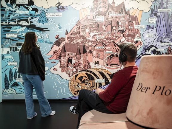 Zwei-Menschen vor einer großen grafischen Wand mit Burganlage