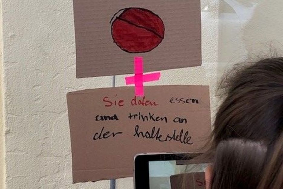 Mädchen fotografiert an eine Glasscheibe geklebte Zettel aus Karton