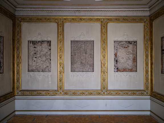 A decorative room wall with bare surfaces on which restored pictures will hang