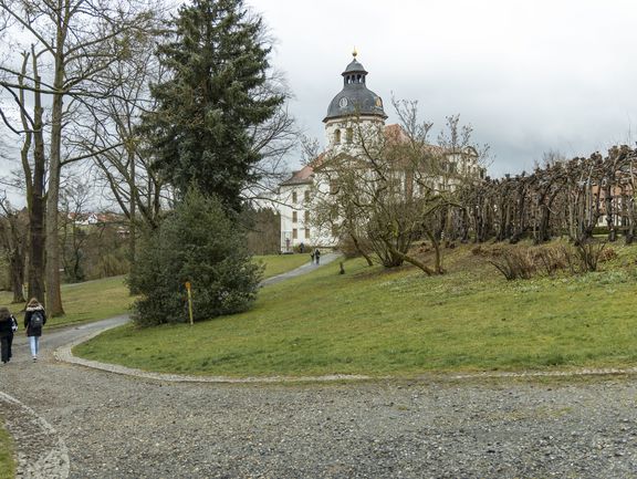 Zwei Jugendliche laufen in einem Park in Richtung des Eisenberger Schlosses