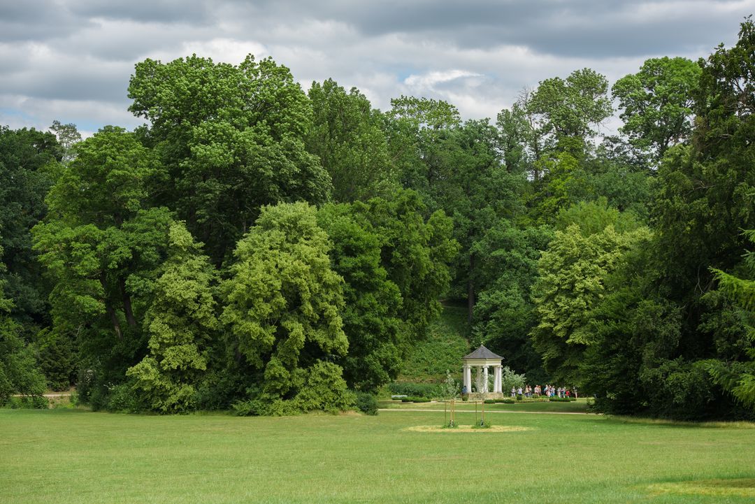 A group of visitors looks at the Temple of the Muses in the park.