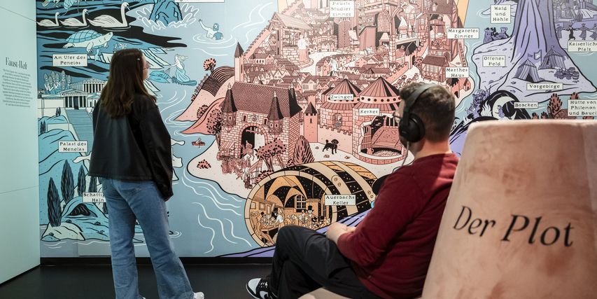 Zwei-Menschen vor einer großen grafischen Wand mit Burganlage